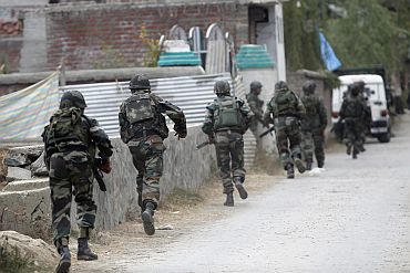 Army soldiers run towards the site of gunbattle with suspected militants in Maloora on the outskirts of Srinagar