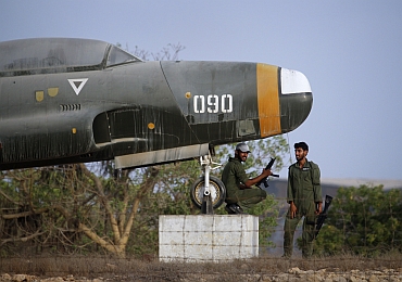 Military personnel keep guard under an old aircraft displayed at the Mehran naval aviation base after troops ended operations against militants in Karachi