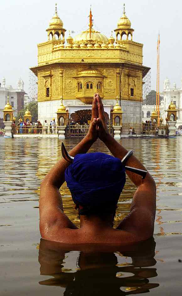 A Sikh devotee takes a dip in the pond at the Golden temple on the birth anniversary of Guru Nanak Dev in Amritsar