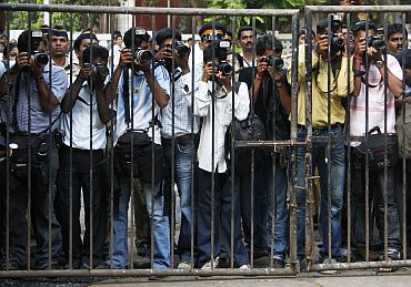 Press photographers in Mumbai stand behind a fence for security reasons as they take pictures of Belgium's Queen Paola in a school in 2008