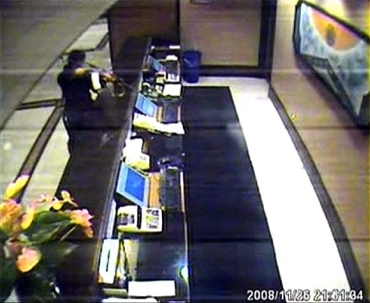 A terrorist aims his weapon at a desk in Trident-Oberoi hotel in this image taken from the hotel's CCTV video footage