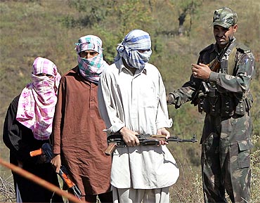 A soldier escorts suspected militants during a surrender ceremony