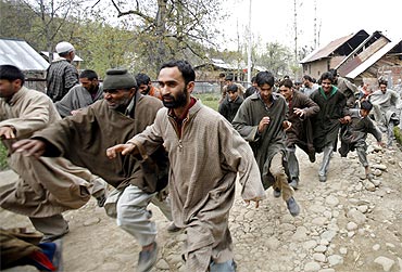 Kashmiri protesters run for cover after army soldiers fired shots into the air to disperse them