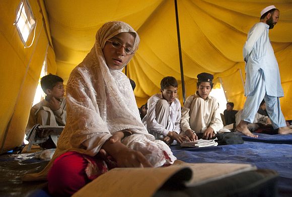 A young girl reads aloud while attending class in a makeshift school tent in Mingora