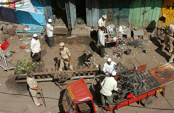 Locals and police officers clear debris at a blast site in Malegaon
