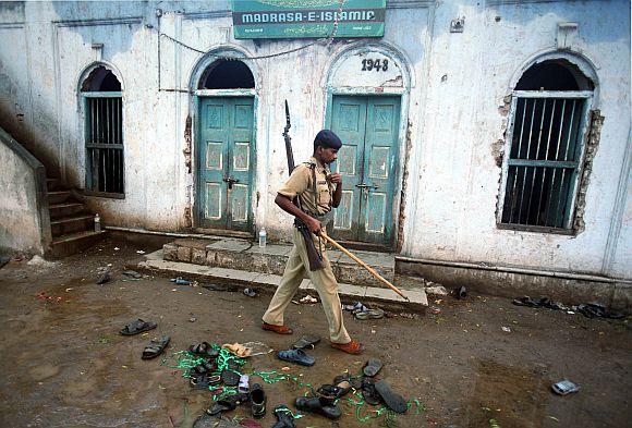 A policeman walks past a clutter of torn slippers of blast victims inside a mosque in Malegaon