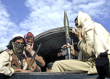 Pakistani Taliban fighters sit with their weapons on the back of a truck in Buner