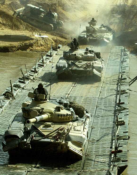 Indian soldiers atop T-72 tanks cross a bridge as they take part in an exercise