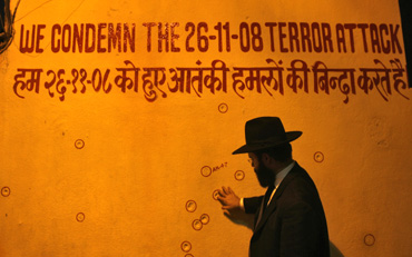 A rabbi touches a wall riddled with bullet holes in front of Nariman House, Mumbai