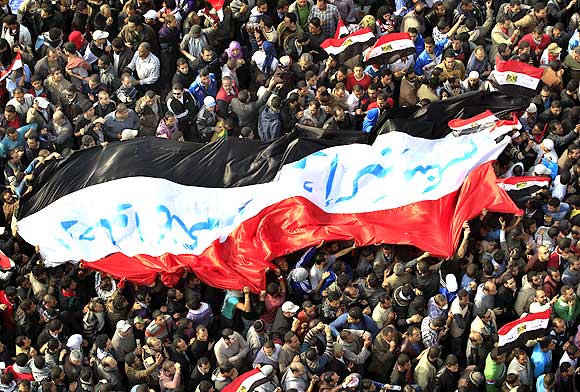 Egyptian protesters march with a huge flag during a rally