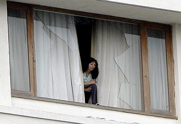 A hotel guest looks out from a broken window of the besieged Trident-Oberoi Hotel in in Mumbai on November 28, 2008