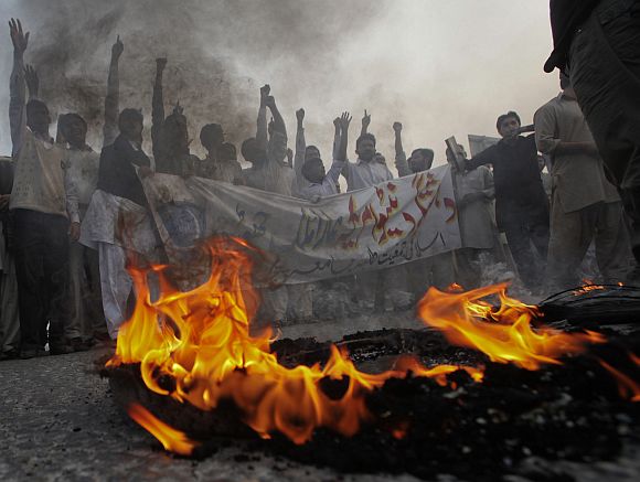 Pakistani students hold a banner while protesting against NATO forces in front of a burning tyre in Lahore on Saturday.