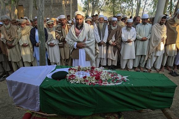 Relatives and residents pray near the flag-draped coffin of solider Najeebullah, who was killed in a Nato cross-border attack