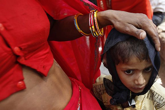 A woman puts her hand on the head of her son, both living with HIV/AIDS, while attending a protest in New Delhi