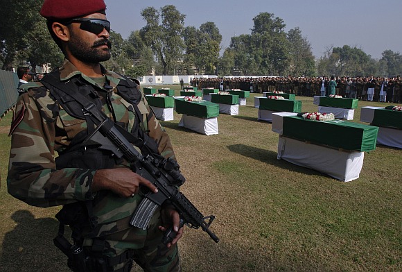 An army soldier stands guard near caskets of soldiers killed in the attack.
