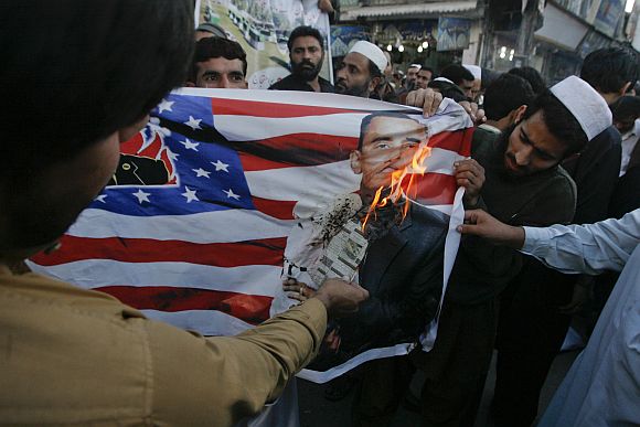 Protesters burn an image of US President Obama printed on the US flag during a demonstration against a NATO cross-border attack in Peshawar