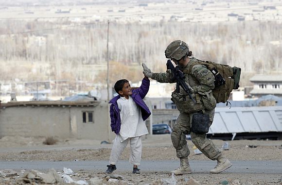 A US soldier takes five with an Afghan boy during a patrol in Pul-e Alam, a town in Logar province, eastern Afghanistan