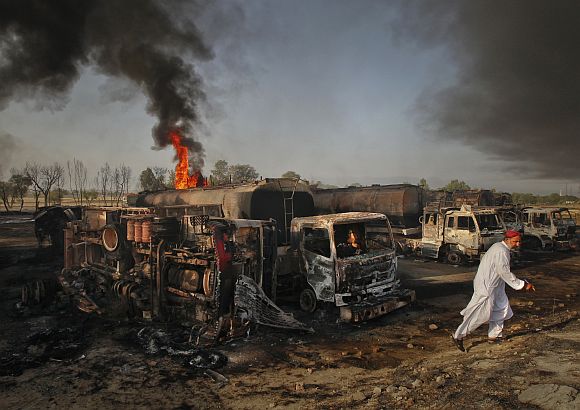 A resident walks past fuel tankers which were set ablaze in Pindi Gheb, some 122 km (76 miles) east of Pakistani capital Islamabad. Gunmen attacked and set fire to eight trucks transporting supplies to NATO forces in Afghanistan in Pakistan's eastern Punjab province