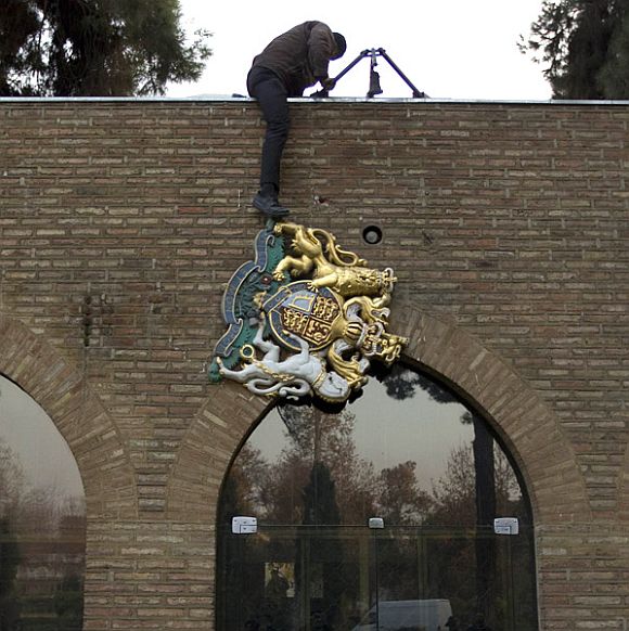 A protesters removes the emblem from the British embassy