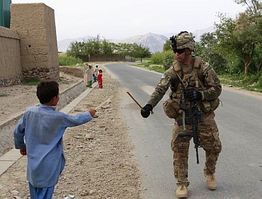 A US soldier uses a stick to play swords with a boy during a patrol in Nangharhar