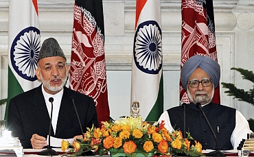 Afghanistan's President Hamid Karzai speaks with the media as Prime Minister Manmohan Singh watches after signing a joint statement at Hyderabad House in New Delhi
