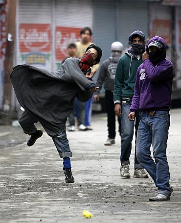 A Kashmiri protester throws stones toward police in Srinagar