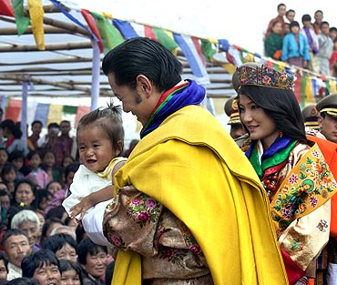 King Jigme Khesar Namgyel Wangchuck holds a child while greeting villagers with Queen Jetsun Pema after their wedding