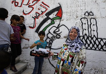 Mufida, the wife of Palestinian prisoner Haled Muheisen, hands out chocolate bars to passers-by outside her home in the East Jerusalem neighbourhood of Issawiya, as she prepares for her husband's release in a prisoner swap that is expected to take place on Tuesday