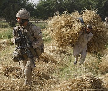A NATO soldier walks past an Afghan man during a patrol