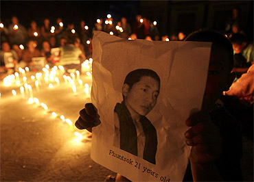 A Tibetan child holds a portrait of Tibetan monk Phuntsog who killed himself through self-immolation