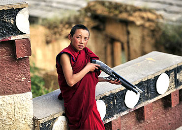 A Tibetan Buddhist monk plays with a toy gun at a local monastery in Diqing, Yunnan province
