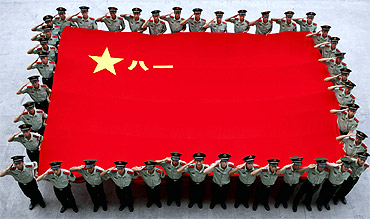 Paramilitary policemen salute as they hold a Chinese People's Liberation Army flag to celebrate the 84th anniversary of the founding of the PLA