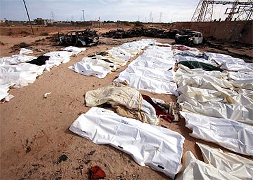 Libyans inspect bodies of Gaddafi loyalists who were killed in an attack on their convoy near Sirte