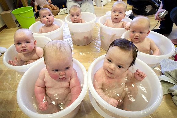 Seven babies sit in tummy tubs filled with water to cool down after a baby massage class held for young mothers in IJmuiden, north of Haarlem, Netherlands