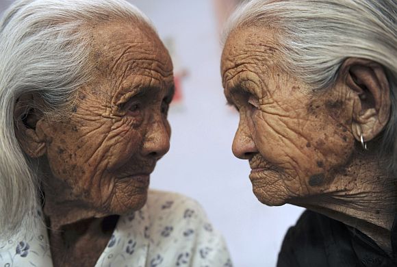 Chinese twins Cao Xiaoqiao (R) and her elder sister Cao Daqiao look at each other on the outskirts of Shiqiaozi town in Zhucheng, Shandong province. They were born in 1905