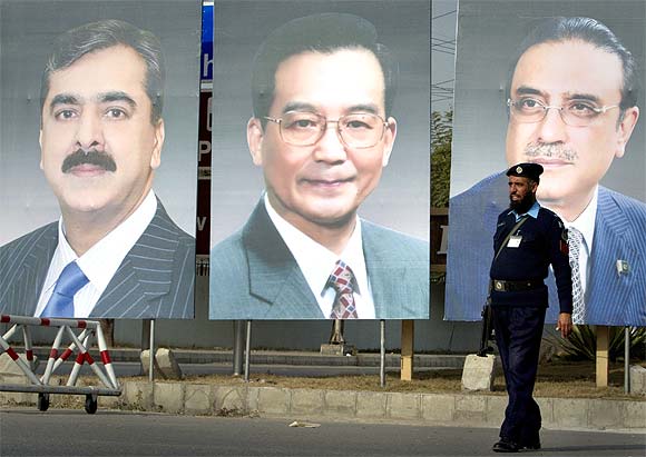 A policeman walks past giant portraits of (from L-R) Pakistan's Prime Minister Yusuf Raza Gilani, China's Premier Wen Jiabao and Pakistan's President Asif Ali Zardari displayed along a road in Islamabad