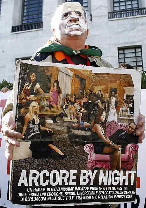 A demonstrator holds up a sign with a picture of Italian Prime Minister Silvio Berlusconi