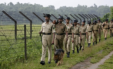 BSF  personnel patrol with a sniffer dog along a stretch of the India-Bangladesh border
