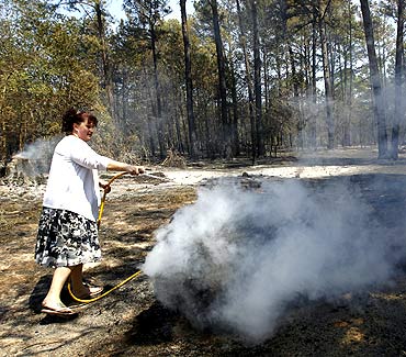 Shelly Silveira hoses down a burning log as she tries to prevent the fire from reaching her house