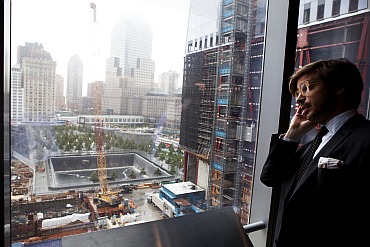 A journalist speaks on his phone as he looks down at the September 11 Memorial behind him during an event to update the public on the pace of development at the World Trade Center site in New York