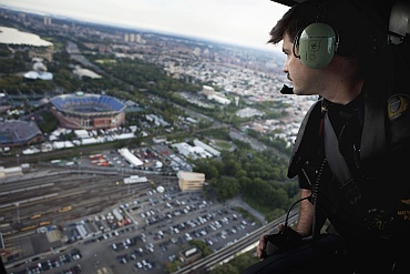 An NYPD officer looks down on the US Open Tennis tournament from a helicopter while on patrol above New York