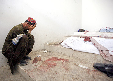 A man mourns next to his dead relative at a morgue, after his body was recovered from the site of a double suicide bombing in Quetta
