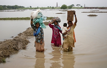 Villagers wade through flood waters with their belongings in the Tando Allahyar, district of Pakistan's Sindh province