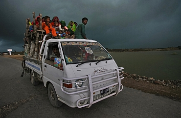 Monsoon clouds are seen as a family flee their flooded village in the Tando Allahyar district of Pakistan's Sindh province