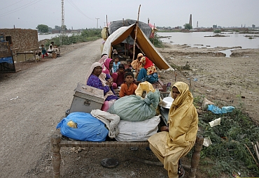 Villagers, who evacuated their flooded villages, sit on higher grounds with their belongings in the Tando Allahyar