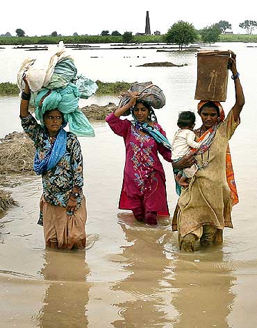 Villagers wade through flood waters with their belongings in the Tando Allahyar district of Pakistan's Sindh province on Monday