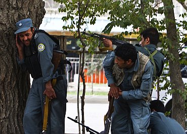 Afghan policemen fire towards a building which the Taliban insurgents took over during an attack near the US embassy in Kabul