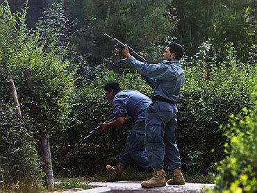 Afghan policemen fire towards a building which the Taliban insurgents took over