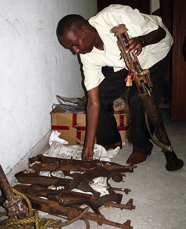 A Kenya Police officer arranges an exhibit of weapons used by suspected Somali pirates at the law court in Mombasa