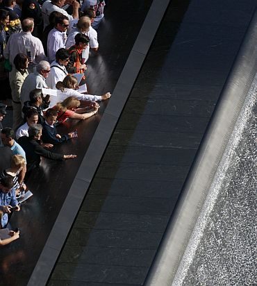 Family members look over one of the Twin Memorial pools at Ground Zero in New York